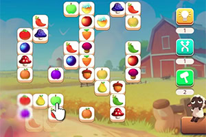 Schermata di un puzzle match con tessere di frutta colorata su uno sfondo di fattoria con fienile rosso e mucca